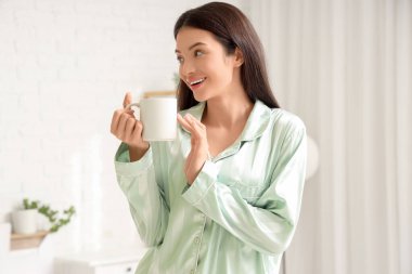 Yatak odasında bir fincan çayla güzel genç bir kadın.