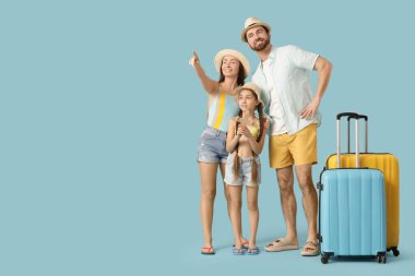 Mavi arka planda bavulları olan mutlu bir aile. Seyahat kavramı