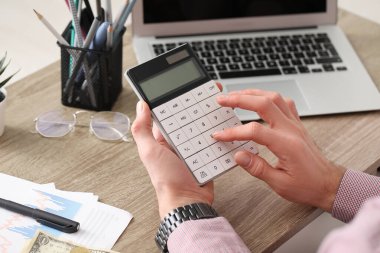 Ofis çalışanı masada hesap makinesiyle sayıyor. Yakın çekim.