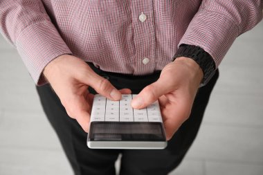 Hesap makinesini ofisinde tutan erkek muhasebeci. Yakın çekim.