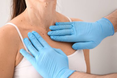 Tıbbi eldivenli cildiyeciler klinikteki kadın hastaların benlerini inceliyor. Yakın çekim.