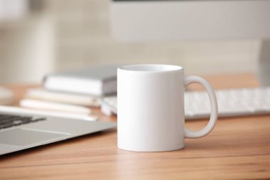 Ofisteki defterlerin yanındaki masada beyaz seramik bardak.