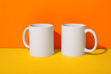 Turuncu duvara karşı sarı masada seramik bardaklar