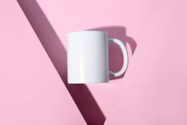 Pembe arka planda seramik beyaz bardak. Üst görünüm