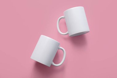 Pembe arka planda beyaz seramik bardaklar. Üst görünüm