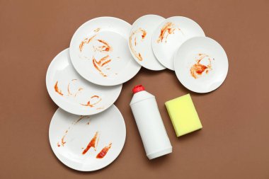 Kirli bulaşıklar, deterjan ve kahverengi arka planda sünger. Üst görünüm