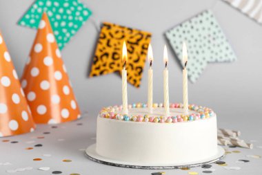 Gri arka planda yanan mumlarla lezzetli bir doğum günü pastası.