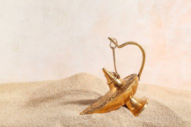 Işık arkaplanda kum bulunan Aladdin lambası