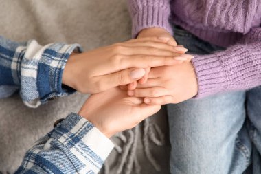 Evlatlık kızla el ele tutuşan genç bir kadın, yakın çekim.