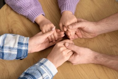 Evlatlık kızı olan çift masanın üstünde el ele tutuşuyor.