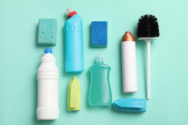 Turkuaz arka planda fırça ve süngerli deterjan şişeleri