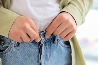 Evde kot pantolon ilikleyen genç adam, yakın çekim.