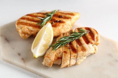 Lezzetli ızgara tavuk göğsü, biberiye, biber ve beyaz arka planda limon dilimi.