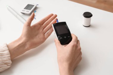 Beyaz masada dijital glukometresi olan kadın