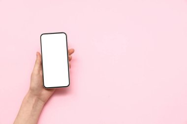 Pembe arka planda cep telefonu olan bir kadın.