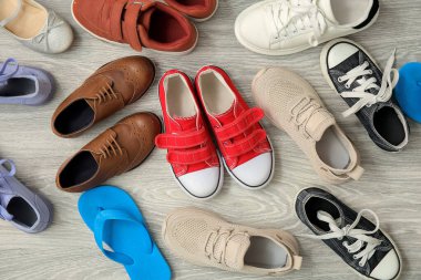 Gri ahşap arka planda farklı çocuk ayakkabıları.