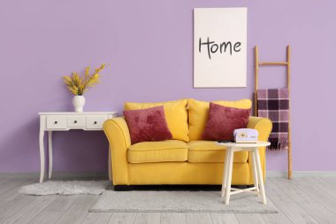 Masasında mimoza çiçekleri olan modern oturma odasının şık bir iç mekanı.