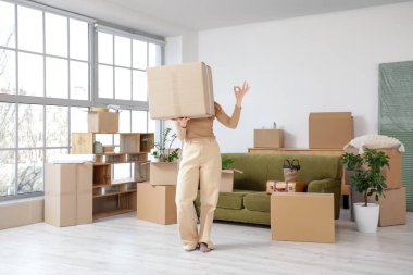 Taşındığı gün odada karton kutu taşıyan genç bir kadın.