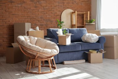 Taşındığı gün odada karton kutuları olan koltuk ve koltuk.