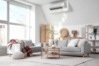 Gri koltukları, kahve masası ve büyük pencereli şık bir oturma odası.