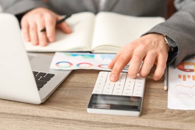 Ofiste hesap makinesiyle çalışan bir iş adamı. Yakın çekim.