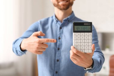 Gülümseyen iş adamı ve modern hesap makinesi ofiste.