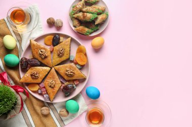 Lezzetli baklava tabağı, geleneksel tatlılar ve pembe arka planda çay. Nowruz Bayram kutlaması