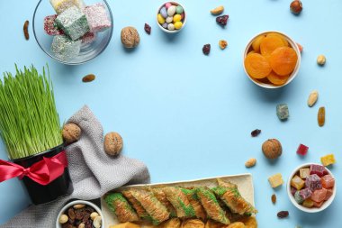 Yeşil buğday otundan yapılmış çerçeve ve mavi arka planda geleneksel tatlılar. Nowruz Bayram kutlaması