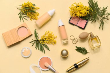 Parfümlü dekoratif kozmetik, şık yüzükler ve sarı arka planda mimoza çiçekleri.