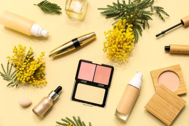 Parfümlü dekoratif kozmetik ürünler ve sarı arka planda mimoza çiçekleri