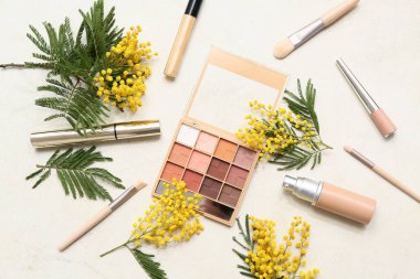 Beyaz arka planda dekoratif kozmetik ve mimoza çiçekleri