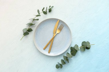 Mavi grunge arka planında okaliptüs dalları olan şık bir masa. Üst görünüm