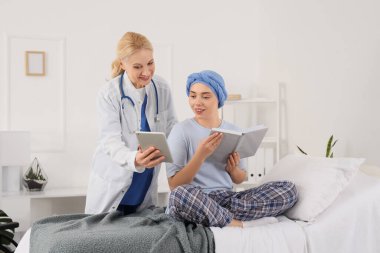 Doktor, kemoterapiden sonra hastane odasında kitapla birlikte genç bir kadına tablet bilgisayar gösteriyor. Beyin kanseri kavramı
