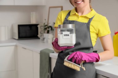 Mutfakta bir kavanoz kabartma tozu ve temizlik fırçasıyla genç bir kadın.