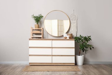 Gri duvardaki ayna ve odanın iç tarafındaki çekmeceler.