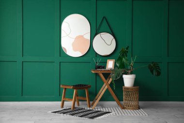 Yeşil duvardaki aynalar, odanın içindeki tabure ve masa.