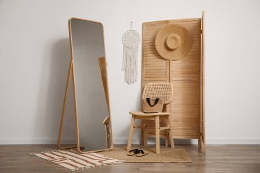 Katlanan ekran, sandalye ve zemin aynası odanın içindeki beyaz duvarın yanında.