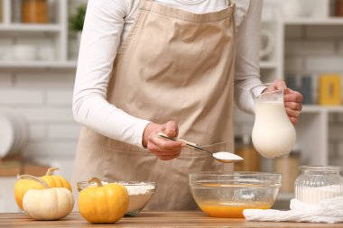 Mutfaktaki masada hamuru hazırlamak için kaseye bir kaşık şeker koyan kadın. Yakın çekim.