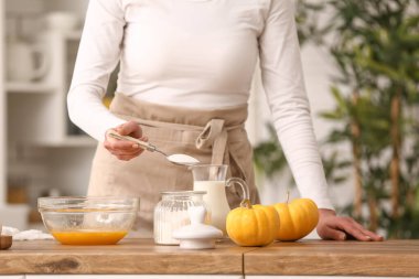 Mutfaktaki masada hamuru hazırlamak için elinde bir kaşık şeker tutan kadın. Yakın çekim.