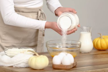 Kadın kaseye şeker ve mutfakta yumurta ekliyor. Yakın çekim.