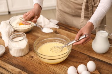 Mutfaktaki masada hamurla kaseye bir kaşık şeker ekleyen bir kadın. Yakın çekim.