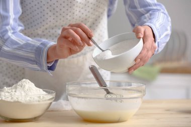 Mutfaktaki masada bir kaşık şekeri hamura koyan kadın. Yakın çekim.