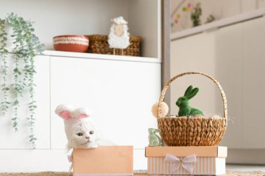 Tavşan kulaklı şirin beyaz kedi hediye kutuları, oyuncak tavşanlar ve mutfakta Paskalya sepeti.