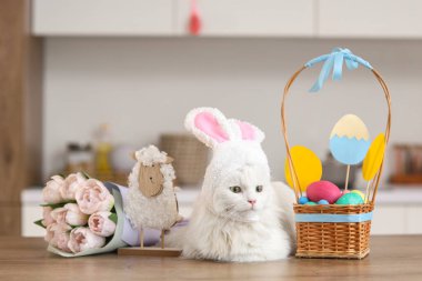 Paskalya sepeti, oyuncak koyun ve mutfaktaki masada duran güzel lale çiçekleriyle tavşan kulaklı şirin beyaz kedi.
