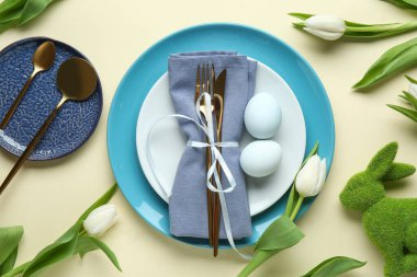 Sarı arka planda lale çiçekleri olan Paskalya kutlaması için şık bir masa.