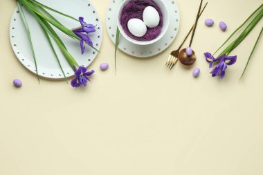 Paskalya kutlaması için bej arka planda süsen çiçekleri olan şık masa ayarları