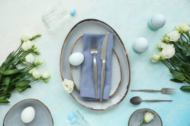 Mavi grunge arka planında östoma çiçekleri olan Paskalya kutlaması için şık masa düzenleme