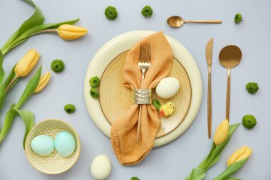 Paskalya kutlaması için gri arkaplanda çiçekler olan şık masa ayarları