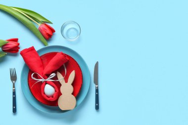 Mavi arka planda lale çiçekleri olan Paskalya kutlaması için şık bir masa.