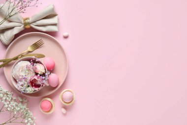 Paskalya kutlaması için masa dekorları pembe arka planda farklı çiçekler.